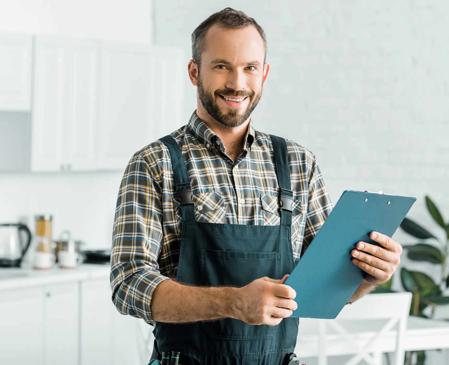 Smiling man holding clipboard in kitchen.