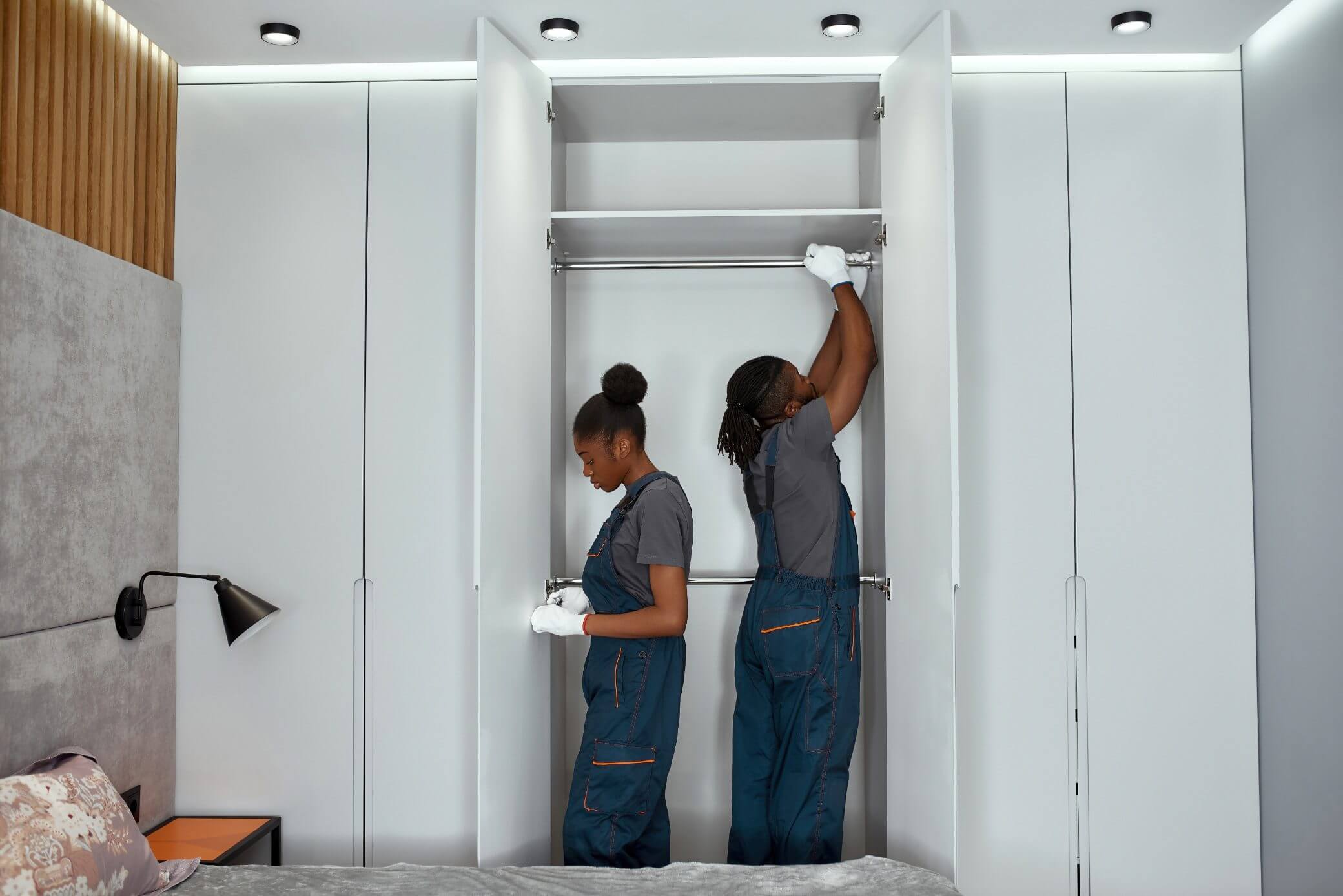 Two workers installing drywall in a room under construction.